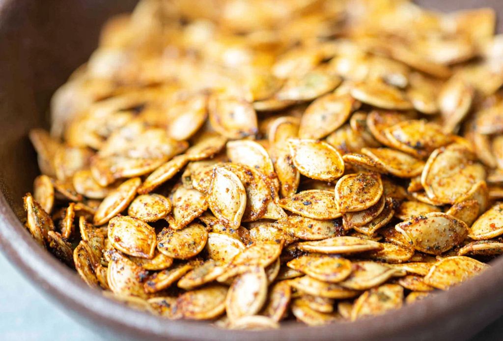 Baking sheet with crispy roasted pumpkin seeds seasoned and golden brown, an easy fall snack.