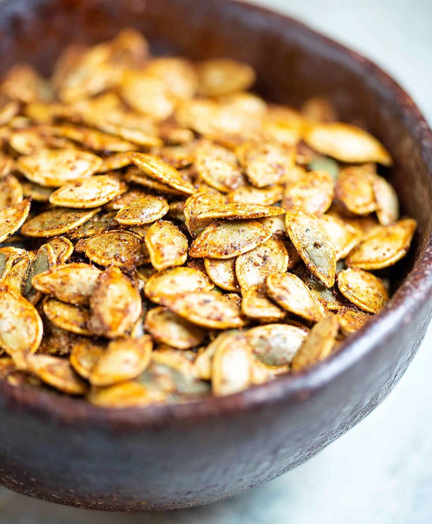 Baking sheet with crispy roasted pumpkin seeds seasoned and golden brown, an easy fall snack.